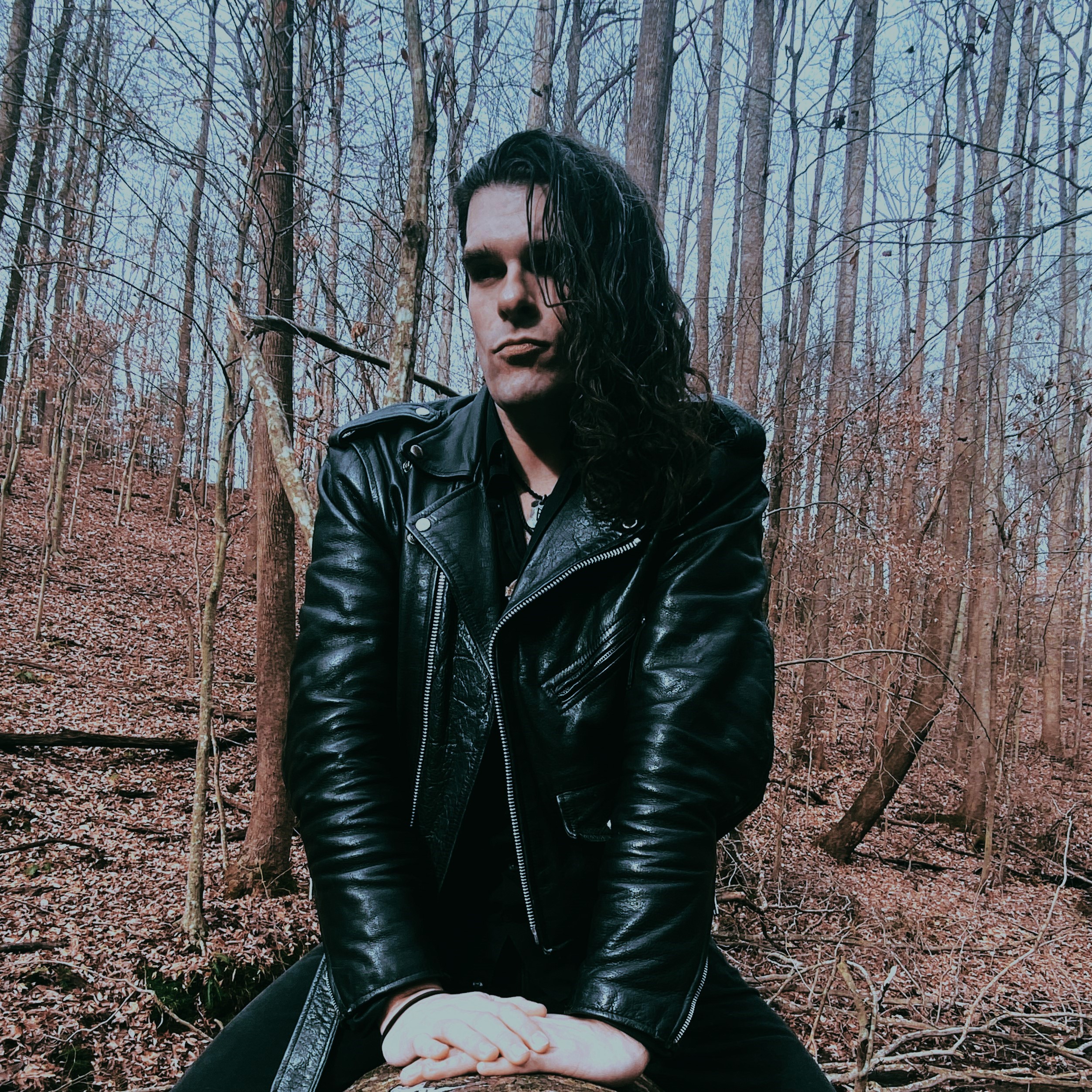 Adam sitting on a log in the woods